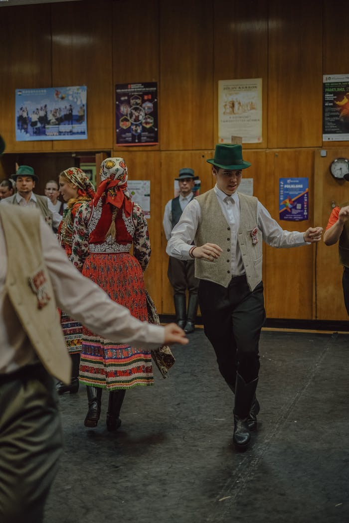 Group of people performing traditional dance in cultural attire with vibrant costumes indoors.